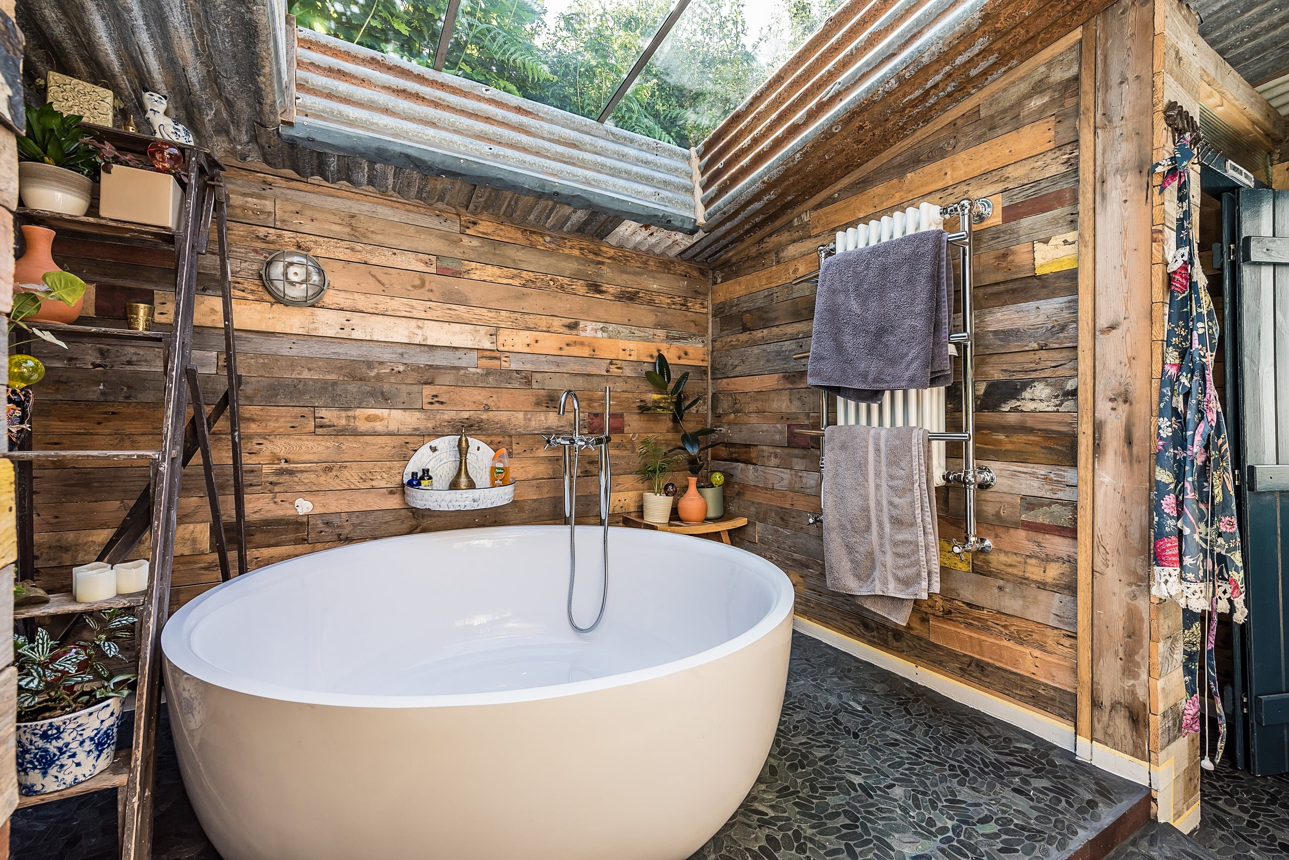 Deep round two-person bathtub under a skylight, surrounded by warm timber